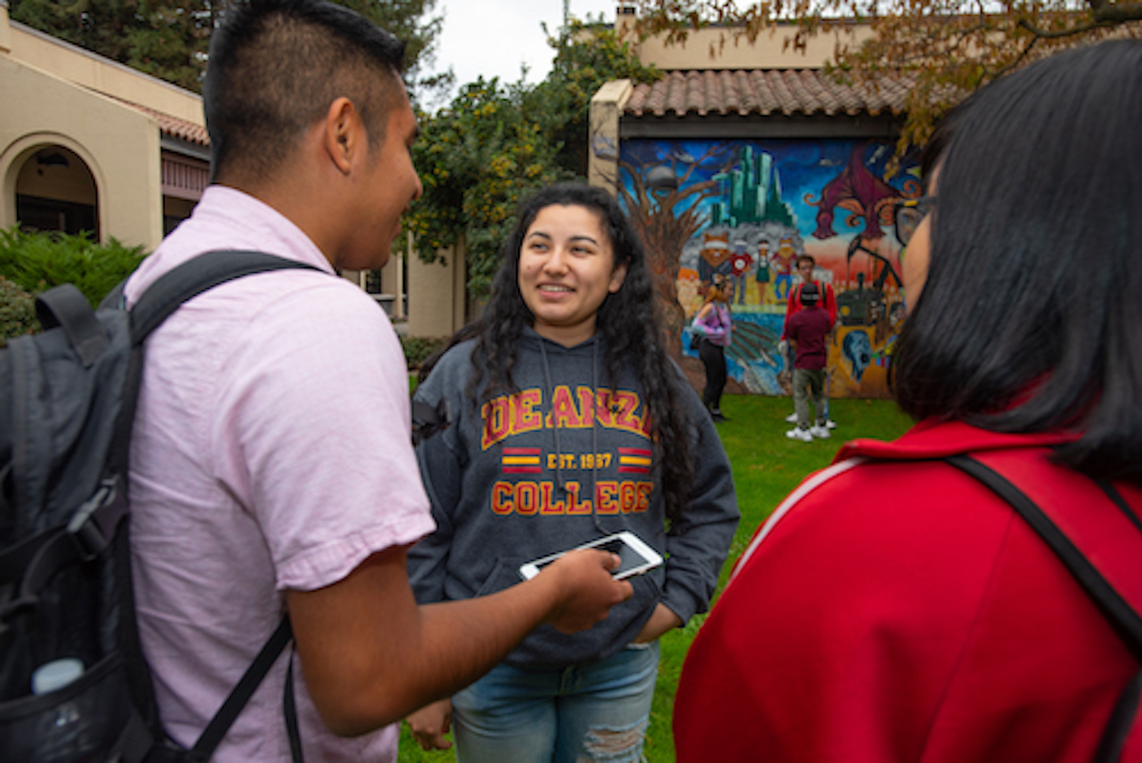 students talking near mural