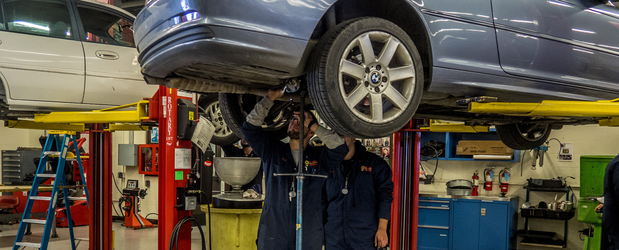 two students inspecting under car