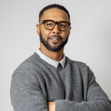 man with glasses and beard and grey sweater crossing arms