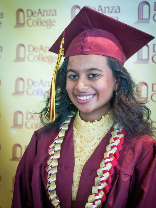 smiling young woman in grad cap and gown over yellow sweater