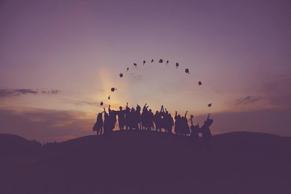 sunrise behind hill with people standing in circle